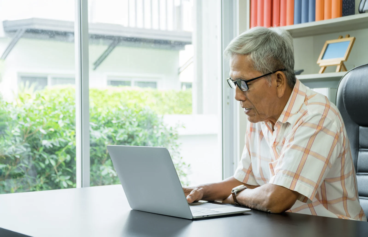Older man sitting at desk completing cognitive screen on laptop