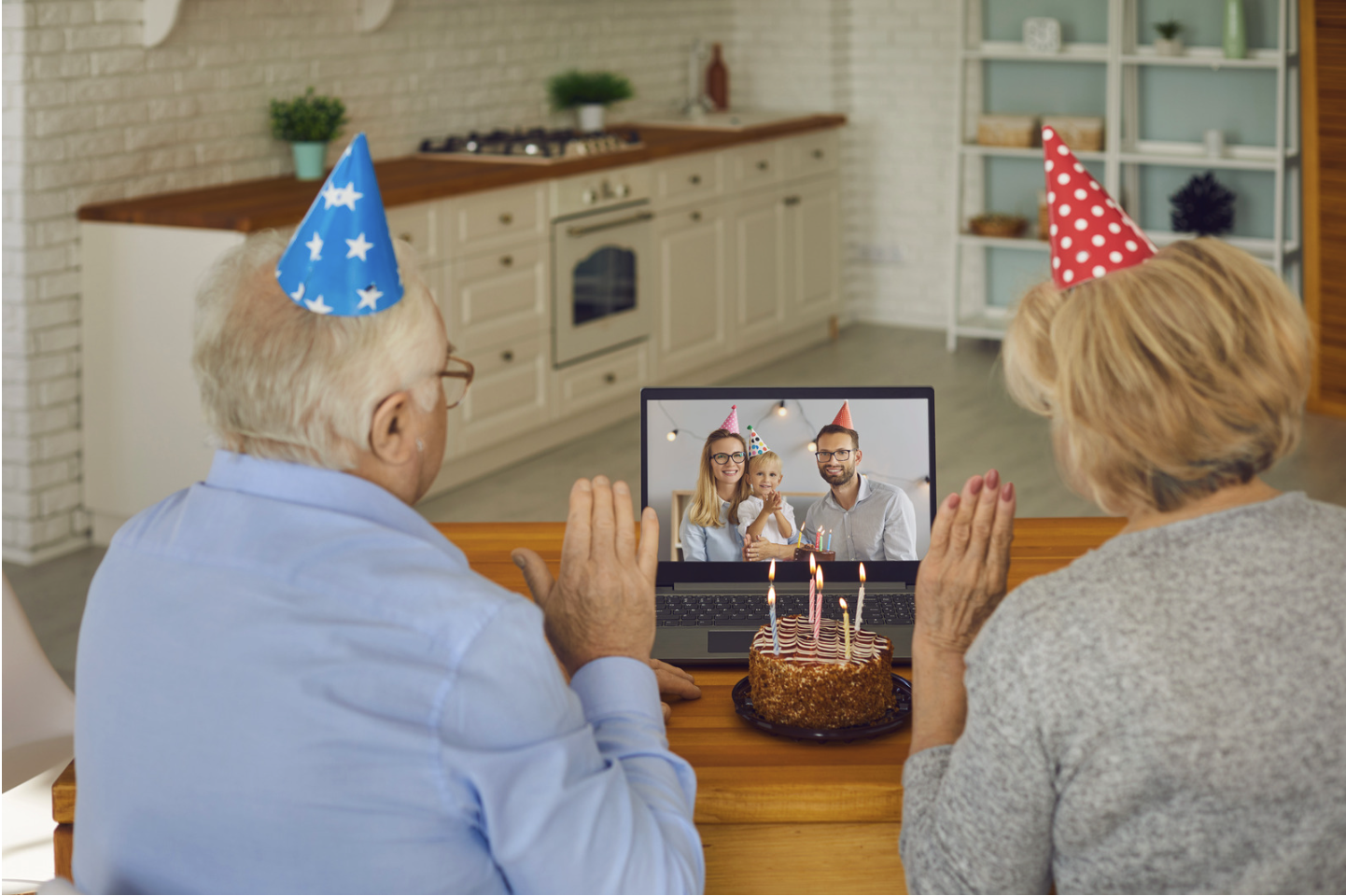 Two older adults celebrating a birthday with family via video call