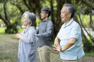 Three Asian adults practicing Tai Chi outdoors