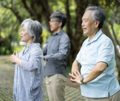 Three Asian adults practicing Tai Chi outdoors
