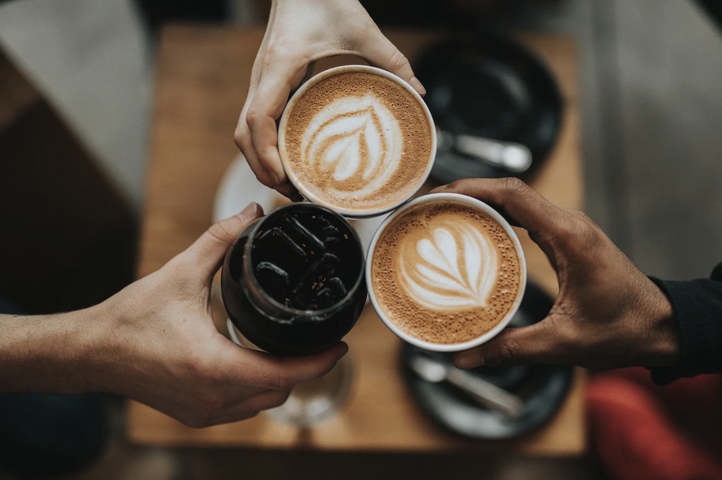 People holding two cups of espresso and one iced coffee