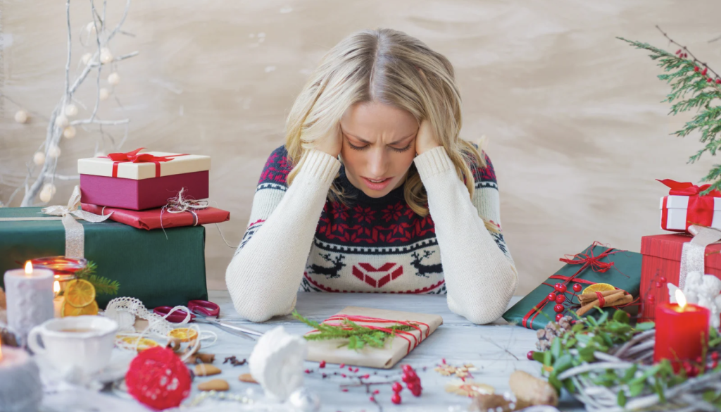 Woman sitting at table with wrapped presents looking stressed