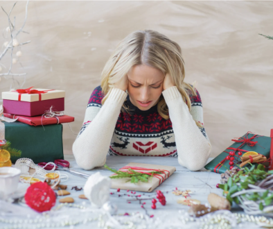 Woman sitting at table with wrapped presents looking stressed